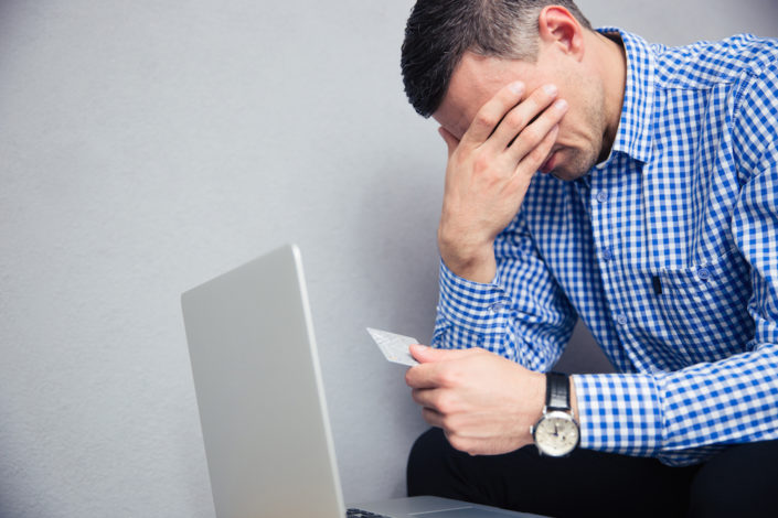Upset man holding credit card financial breakup