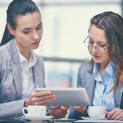 Image of two confident businesswomen working with touchpad in office