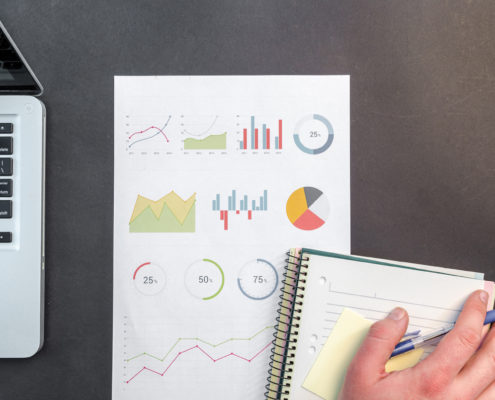 Laptop, a sheet of diagrams and notebook on a desk