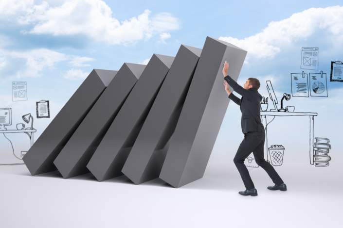 Businessman with his hands up against falling blocks