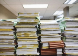 Stacks of papers representing the process and paperwork used in a business lien search process