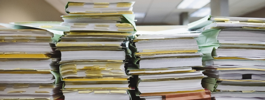 Stacks of papers representing the process and paperwork used in a business lien search process